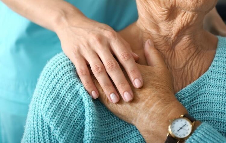 Doctor supporting elderly woman in clinic, closeup